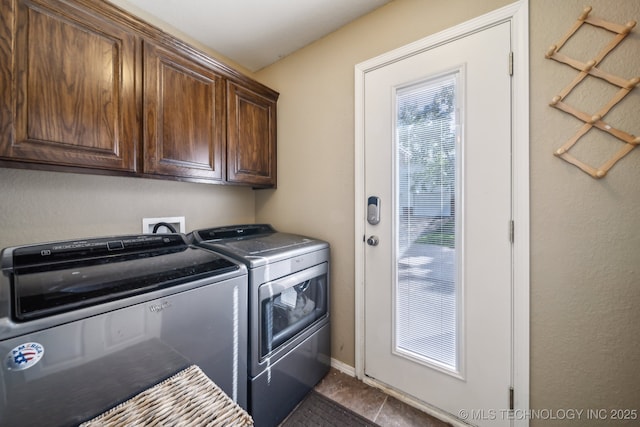 laundry area with dark tile patterned flooring, cabinet space, and washer and dryer