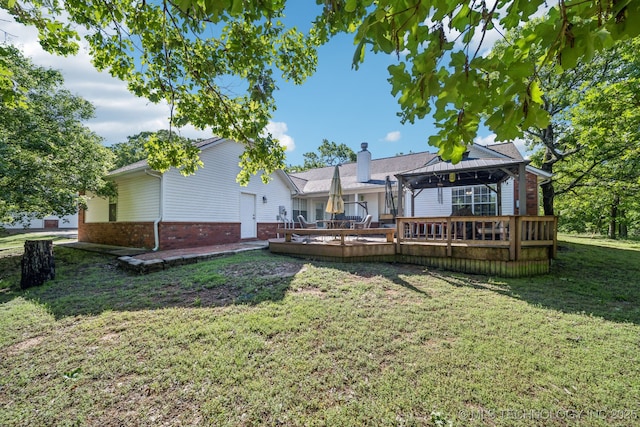 rear view of house with a gazebo, brick siding, a deck, a chimney, and a yard