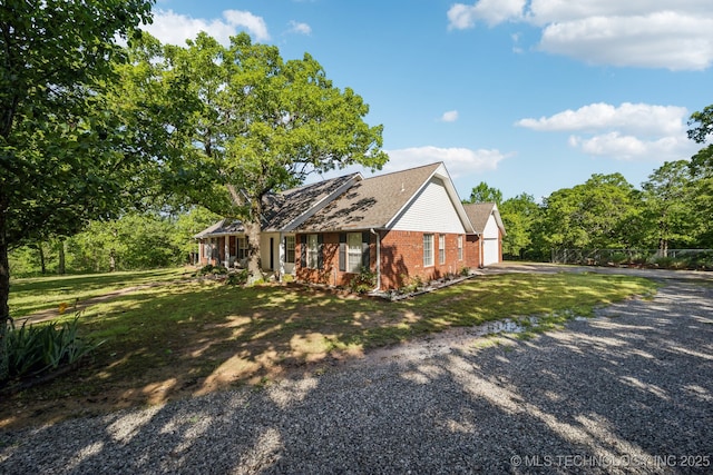 view of front of property with a front yard, a garage, brick siding, gravel driveway, and a shingled roof