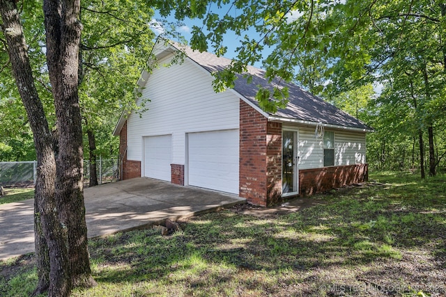 view of home's exterior with brick siding, roof with shingles, and fence