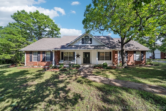 view of front facade featuring brick siding, a shingled roof, a front lawn, and a porch