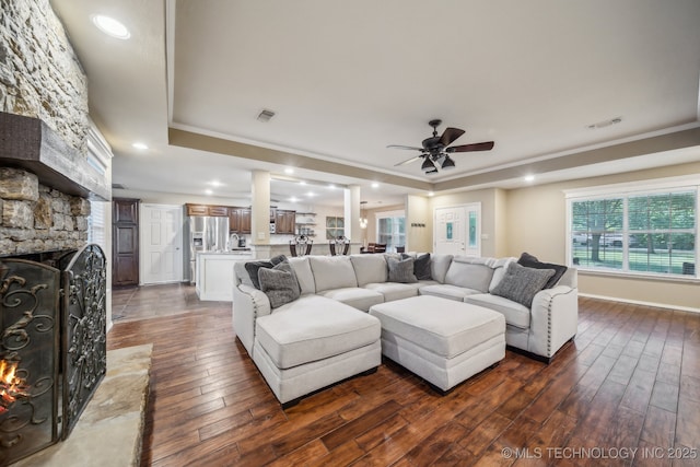 living area featuring dark wood-type flooring, ornamental molding, a tray ceiling, and visible vents
