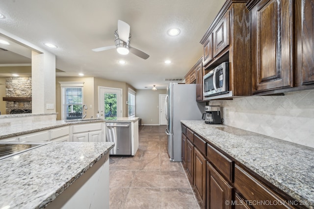 kitchen featuring ceiling fan, appliances with stainless steel finishes, dark brown cabinetry, a sink, and backsplash