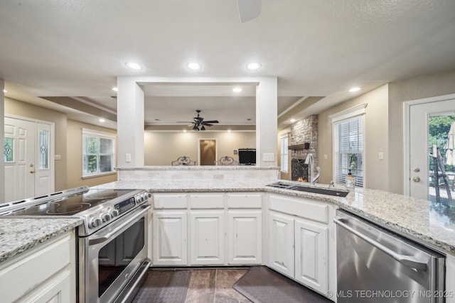 kitchen featuring ceiling fan, white cabinets, a tray ceiling, a sink, and appliances with stainless steel finishes
