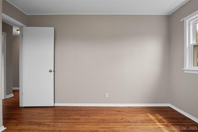 unfurnished room featuring crown molding, baseboards, and wood finished floors