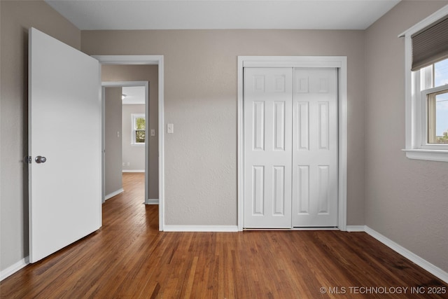 unfurnished bedroom with baseboards, a closet, and wood finished floors