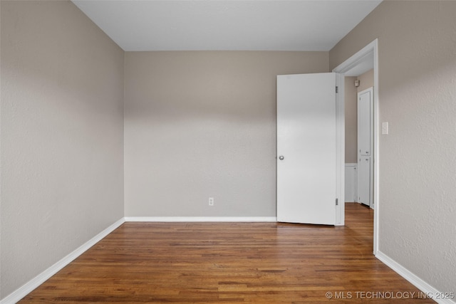 spare room with baseboards and wood finished floors
