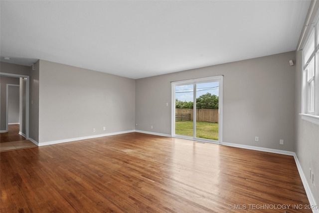 unfurnished living room with baseboards and wood finished floors