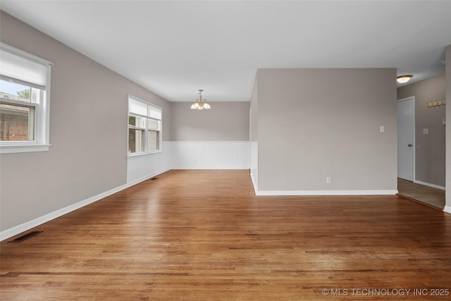 unfurnished room featuring visible vents, light wood finished floors, baseboards, and a chandelier