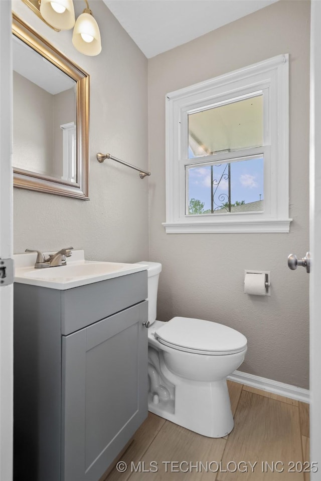 bathroom with toilet, baseboards, wood finished floors, and vanity