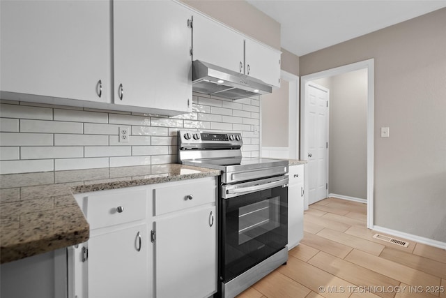 kitchen with visible vents, baseboards, backsplash, exhaust hood, and stainless steel range with electric cooktop