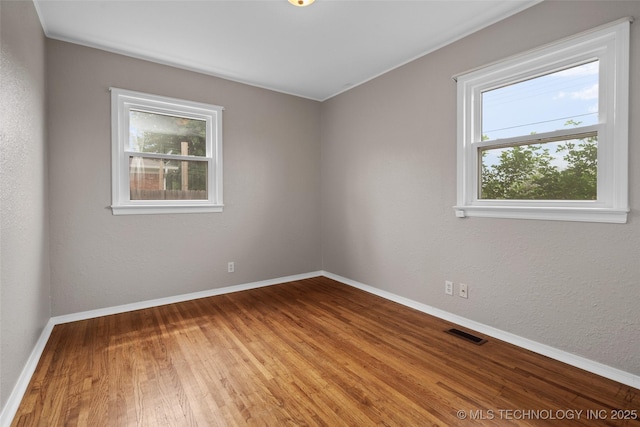 spare room featuring baseboards, visible vents, and wood finished floors
