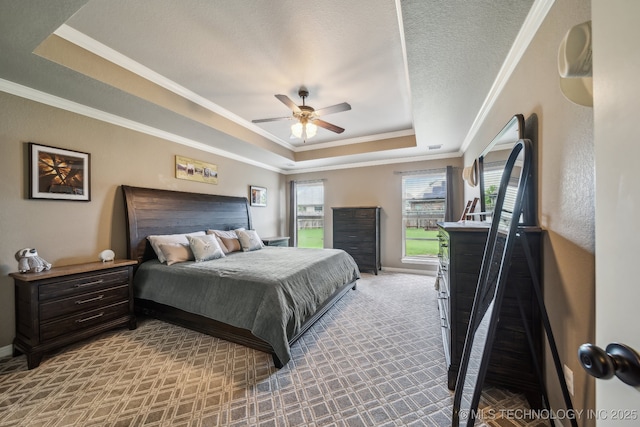 bedroom with ceiling fan, a raised ceiling, baseboards, carpet floors, and ornamental molding