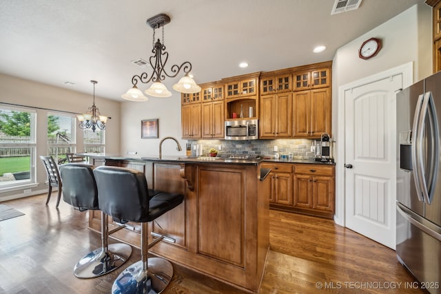 kitchen with brown cabinets, dark wood-style flooring, a notable chandelier, and appliances with stainless steel finishes