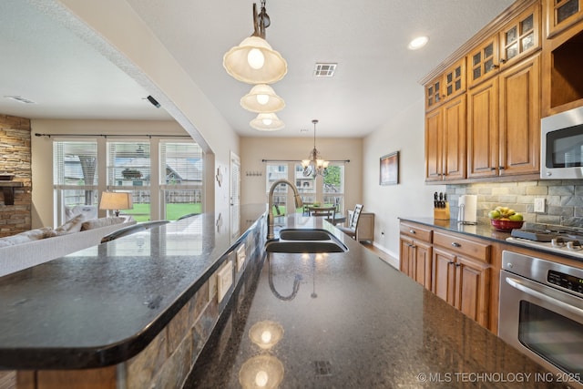kitchen featuring visible vents, appliances with stainless steel finishes, tasteful backsplash, a sink, and an inviting chandelier