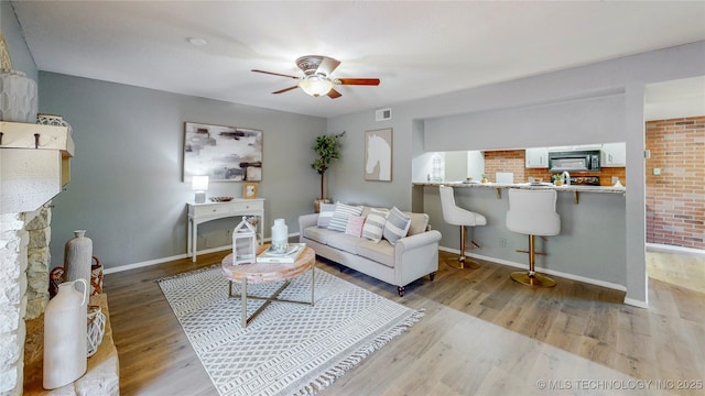 living room with baseboards, a ceiling fan, wood finished floors, and visible vents