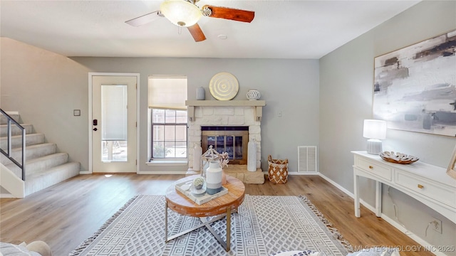 living room with stairs, a ceiling fan, baseboards, wood finished floors, and visible vents