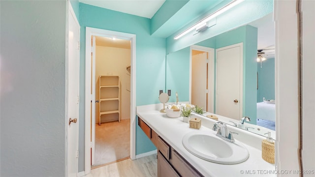 bathroom featuring vanity, baseboards, and ensuite bath