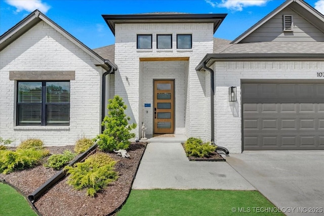 contemporary home with an attached garage, concrete driveway, and brick siding