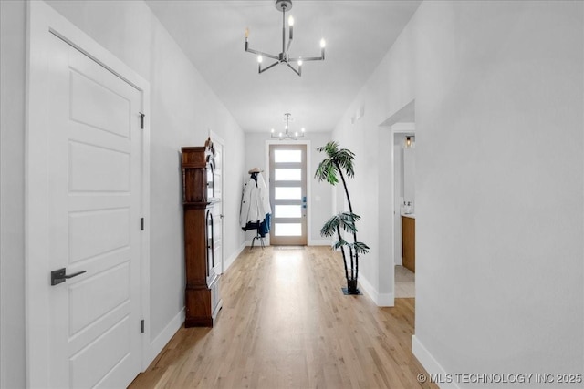 entrance foyer with an inviting chandelier, baseboards, and light wood finished floors