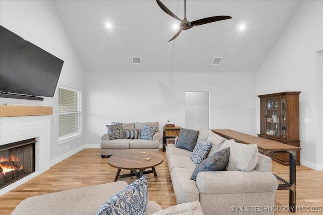 living room with visible vents, ceiling fan, wood finished floors, and a fireplace