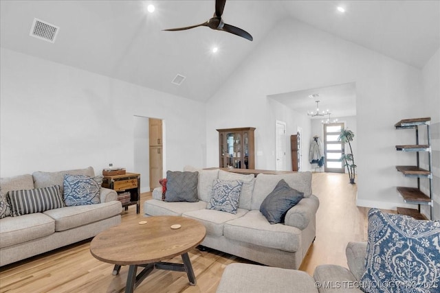 living area with high vaulted ceiling, ceiling fan with notable chandelier, wood finished floors, and visible vents