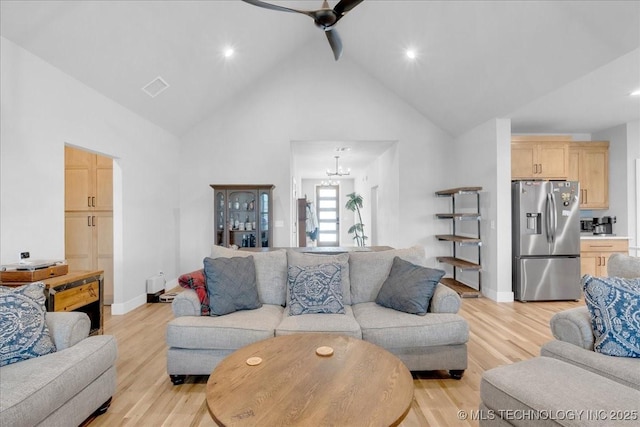 living area with visible vents, light wood finished floors, ceiling fan with notable chandelier, and high vaulted ceiling
