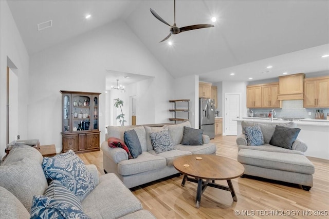living area with light wood-style floors, high vaulted ceiling, ceiling fan with notable chandelier, recessed lighting, and visible vents
