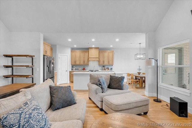 living area with recessed lighting, baseboards, a notable chandelier, and light wood finished floors