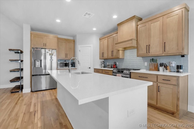 kitchen featuring visible vents, light wood-type flooring, tasteful backsplash, a sink, and appliances with stainless steel finishes