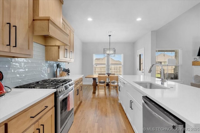 kitchen featuring light countertops, stainless steel appliances, a sink, and light wood finished floors