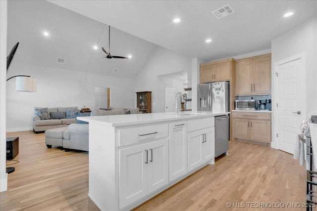 kitchen with a sink, light wood-style floors, light countertops, stainless steel appliances, and visible vents
