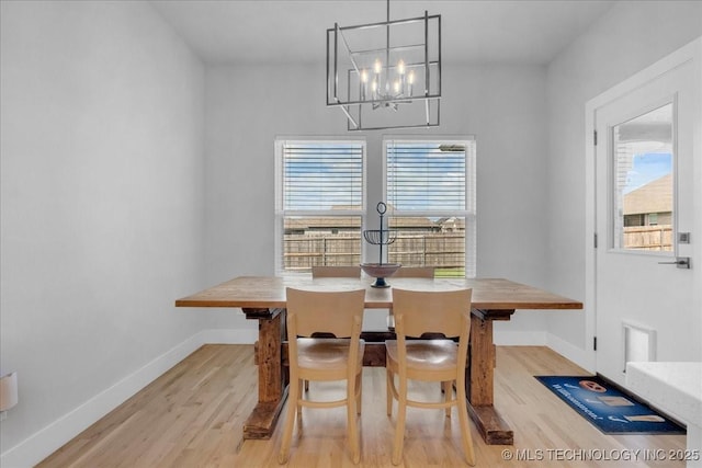 dining area with baseboards, an inviting chandelier, a wealth of natural light, and wood finished floors