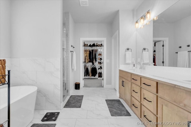 bathroom featuring double vanity, a shower stall, a walk in closet, and marble finish floor