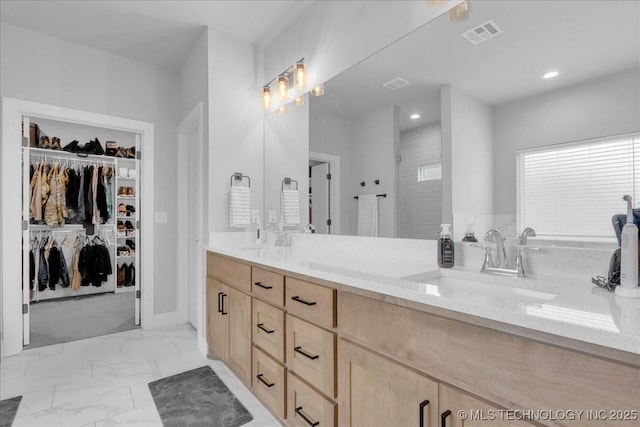 bathroom with a sink, double vanity, marble finish floor, a spacious closet, and visible vents