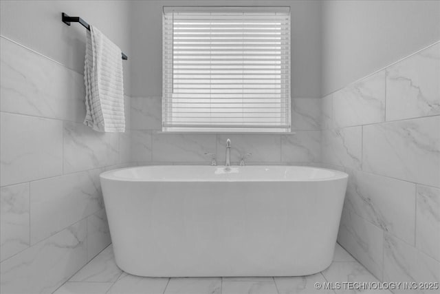 full bathroom featuring marble finish floor, a wealth of natural light, and tile walls
