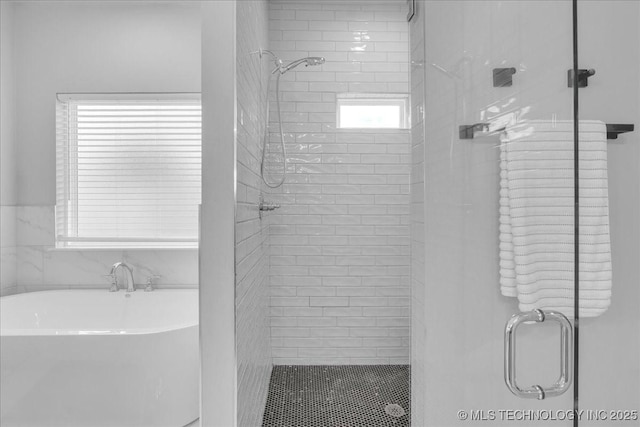bathroom with a shower stall and a soaking tub