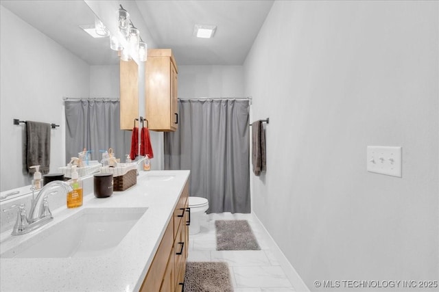 bathroom with double vanity, a sink, baseboards, toilet, and marble finish floor