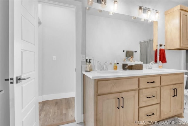 full bath with double vanity, a sink, and wood finished floors