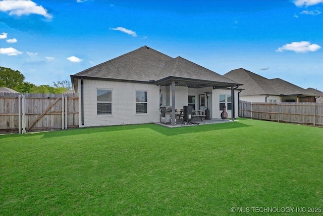 back of property featuring a shingled roof, brick siding, a fenced backyard, a lawn, and a patio