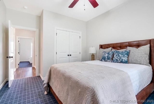 bedroom with baseboards, a ceiling fan, a closet, and dark colored carpet