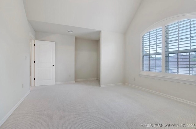 spare room featuring baseboards, carpet, vaulted ceiling, and visible vents