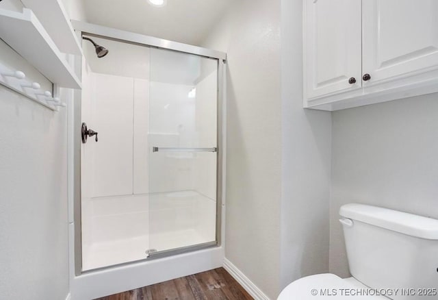 bathroom featuring baseboards, a shower stall, toilet, and wood finished floors