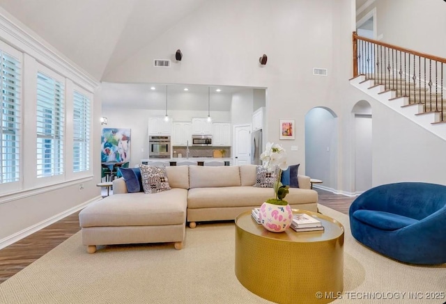 living room featuring high vaulted ceiling, baseboards, wood finished floors, and visible vents