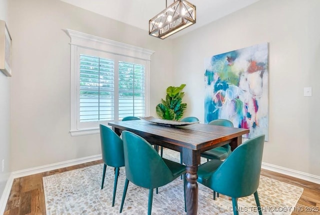 dining area featuring baseboards, wood finished floors, a chandelier, and a healthy amount of sunlight
