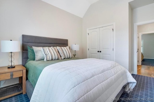 bedroom with a closet, baseboards, vaulted ceiling, and wood finished floors