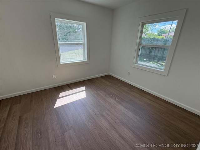 spare room featuring dark wood-type flooring and baseboards