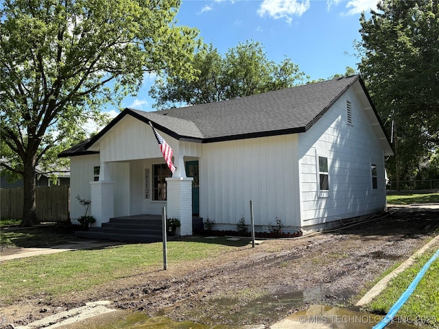 view of front of house featuring fence, a shingled roof, and a porch