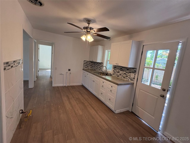 kitchen featuring visible vents, dark countertops, dark wood finished floors, a sink, and white cabinets