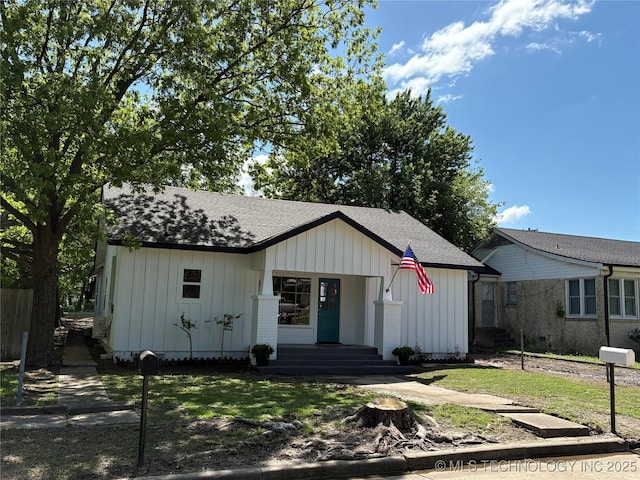 bungalow-style house with board and batten siding, a porch, roof with shingles, and a front lawn